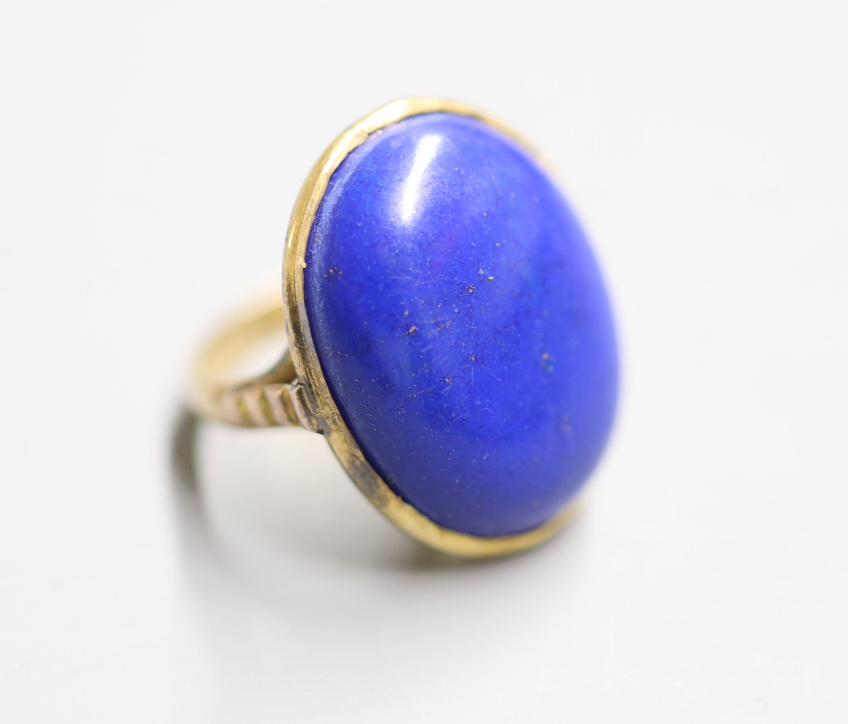 An early 20th century yellow metal and cabochon lapis lazuli set dress ring, size J, gross 8.4 grams (a.f.),